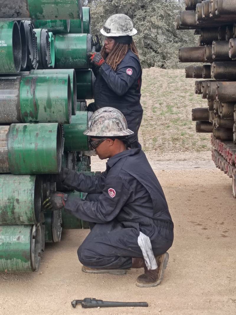 Two A.E. & Sons crew members in hard hats, safety glasses, gloves and coveralls working at the box ends of stacked casing.